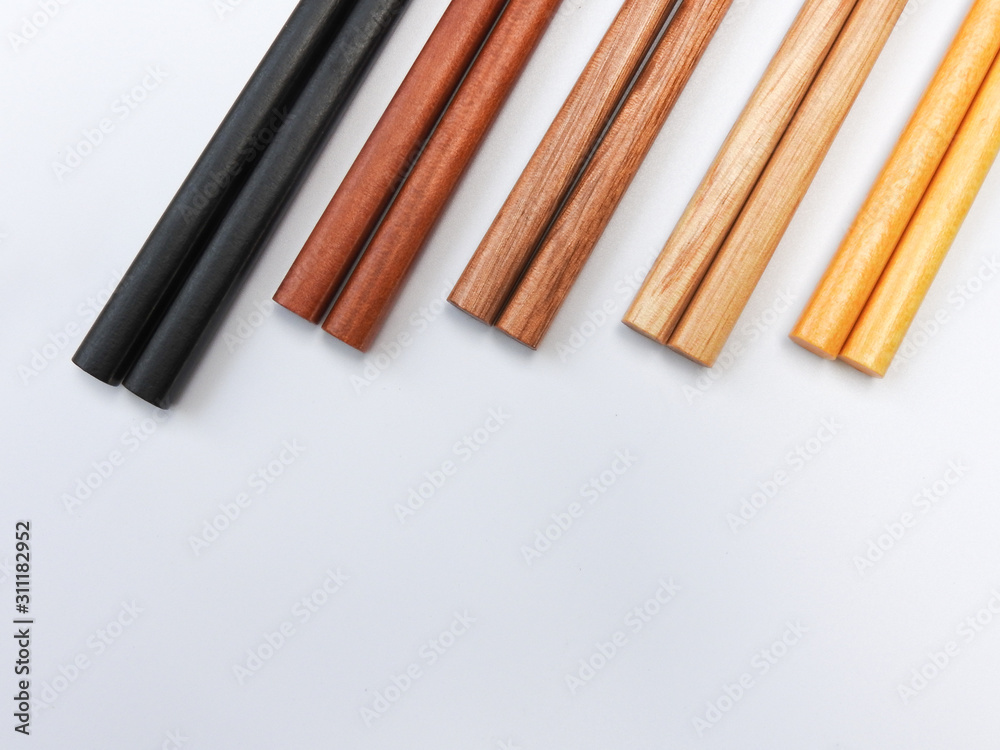 Top view of five color wooden chopsticks are arranged isolated on white background. Main tableware in East and Southeast Asia. Traditional culture and lifestyle concept. With copy space. Top view of five color wooden chopsticks are arranged isolated on white background. Main tableware in East and Southeast Asia. Traditional culture and lifestyle concept. With copy space.