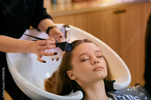 young caucasian female hairdresser dyeing hair to beautiful girl with long hair. Getting beauty procedures.