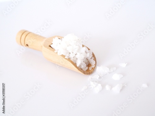 Sea salt in wooden scoop isolated on white background.