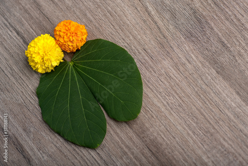 Indian Festival Dussehra, showing golden leaf (Bauhinia racemosa) and marigold flowers on a wooden background. photo