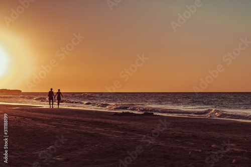 couple silhouettes walking on the beach at sunset in Cuba