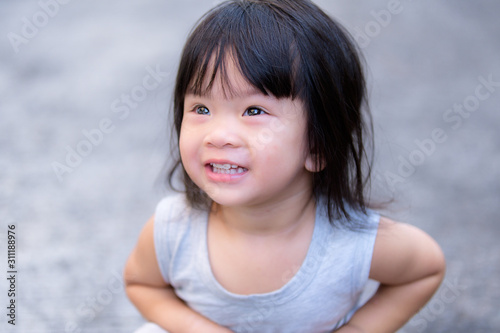 Thai Happy Asian Child Girl after poo poo. She sitting and smiley after she shit out due to constipation. In the evening. She wearing a gray sleeveless dress. Sweet smiling. Baby ages 2 years 4 months