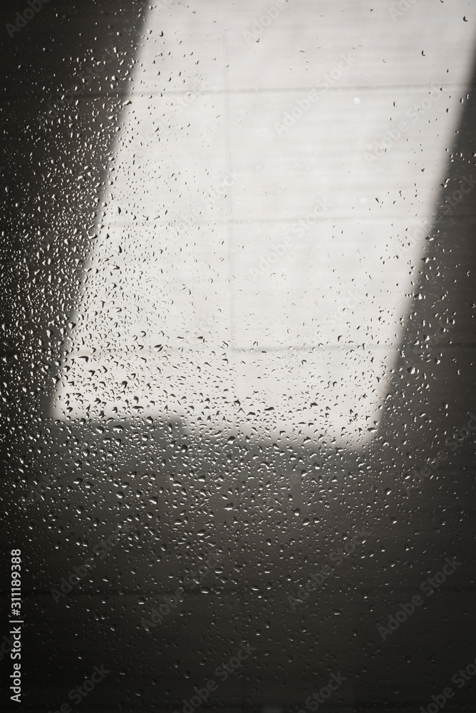 Fototapeta premium Light and shadow on shower wall covered with droplets of water