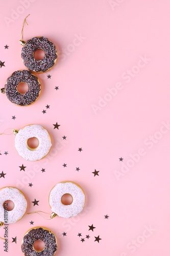 Christmas decoration donuts on a pastel pink background. New Year and Christmas creative concept. Top view, flat lay.