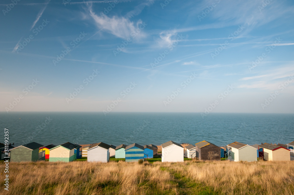 Colourful beach huts against a cloudy sky and facing the  sea.