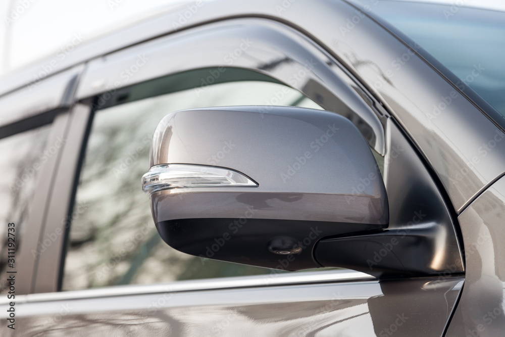 Close-up of the side left mirror with rear veiw 3d camera and window of the car body gray SUV on the parking after washing in auto service industry. Road safety while driving