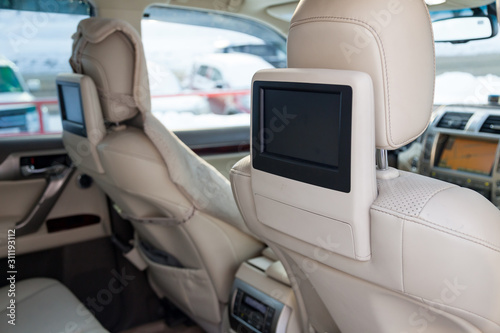 Entertainment system for rear passengers in a car with two monitors mounted on the backs of the front seats for watching TV, cartoons and computer games. © Aleksandr Kondratov
