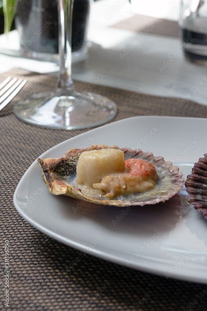 Baked scallops with cheese and spicy sauce. Delicate clam is a real pleasure. Romantic dinner at a Spanish fish restaurant. Mallorca Island, Spain.