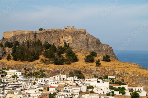 Scenic view at the city of Lindos with white houses, the antique Acropolis on top of the mountain and the bay