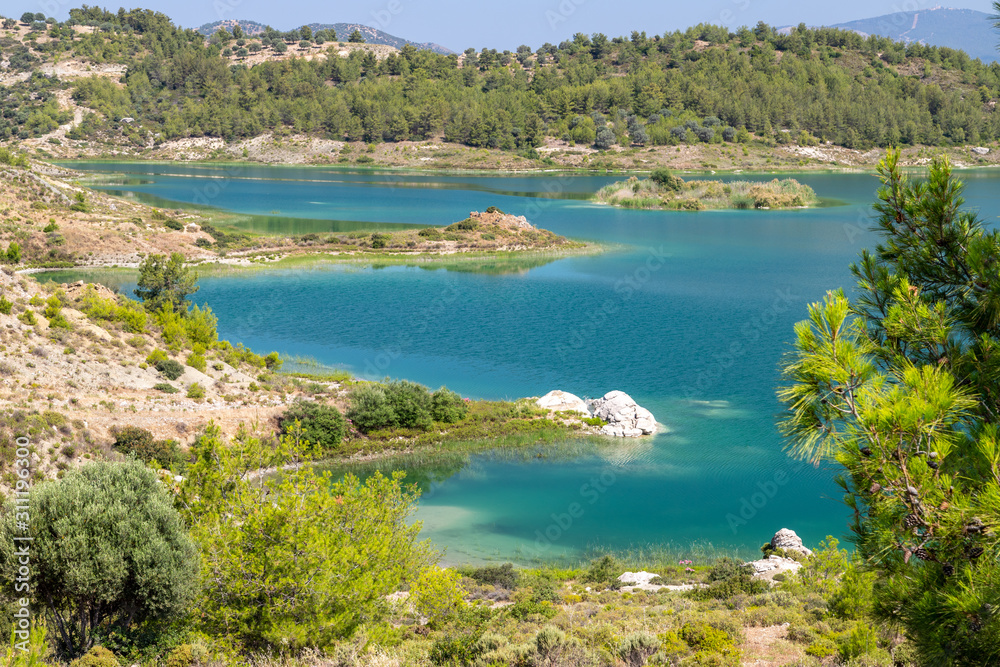 Scenic view at the Gadoura water reservoir on Rhodes island, Greece with blue and turquoise water and green landscape around the lake