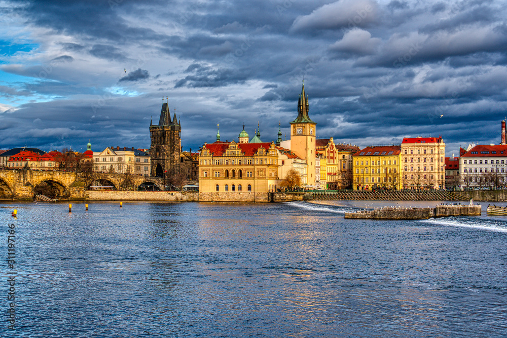 Naklejka premium Beautifully illuminated Charles Bridge at sunset with surrounding buildings, Prague