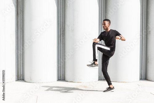 Athletic young afroamerican man running on the promenade. Black Male runner sprinting outdoors. Healthy lifestyle concept. © xartproduction