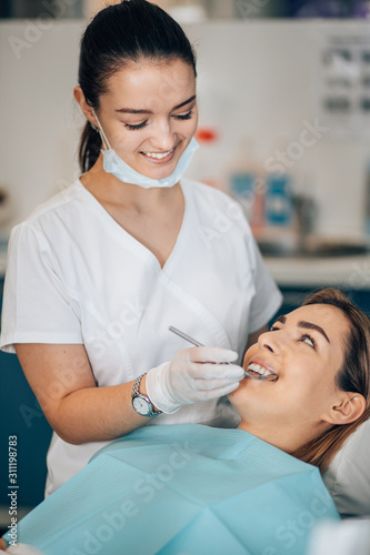 friendly dentist woman treating beautiful patient in dental office, doctor in white uniform, professional orthodontist