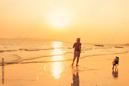 A man and a dog running on the beach and sunset, sunrise.