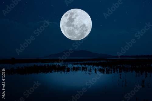 Bright moon over lake at night.