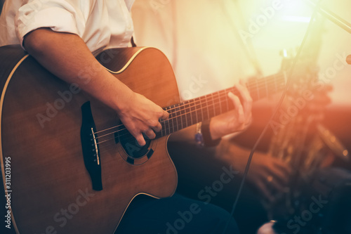hands playing acoustic guitar on the stage, close up