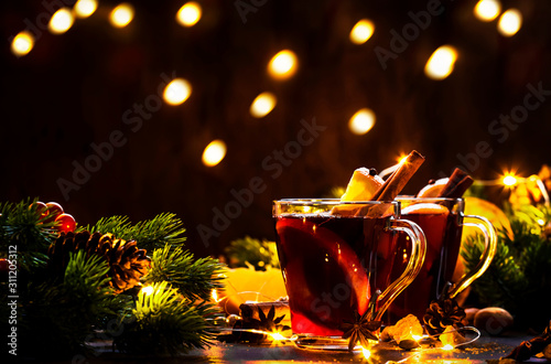 Christmas mulled red wine with spices and fruits on wooden rustic table. Traditional Christmas hot drink in festive light table setting