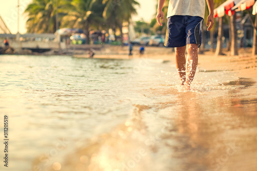 A man walking on the beach and sea water flow with water splash.