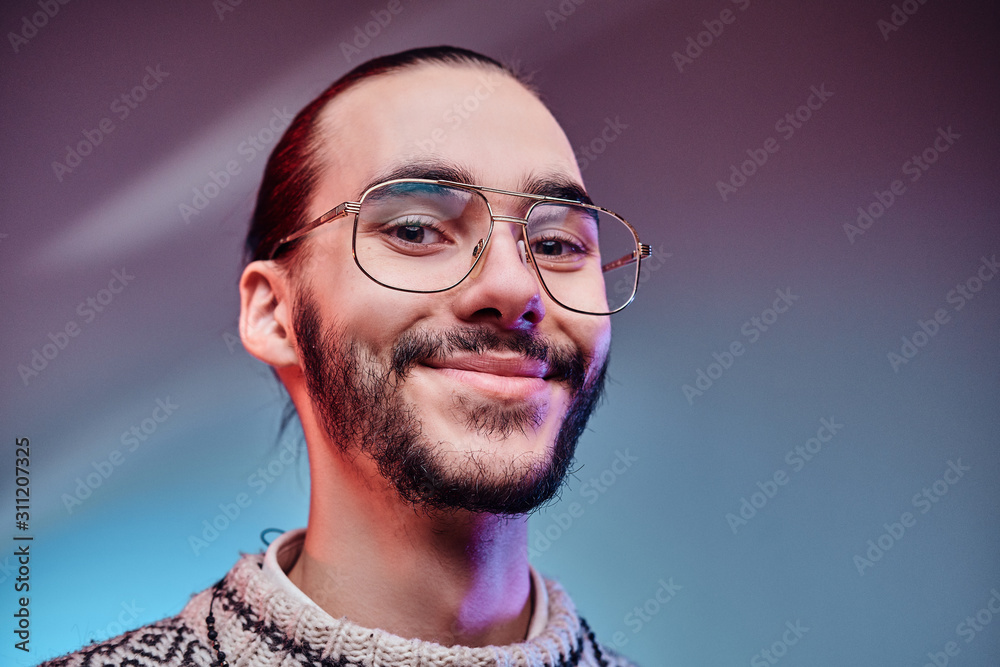 Obraz premium Happy smiling man in winter sweater is posing for photographer at studio.