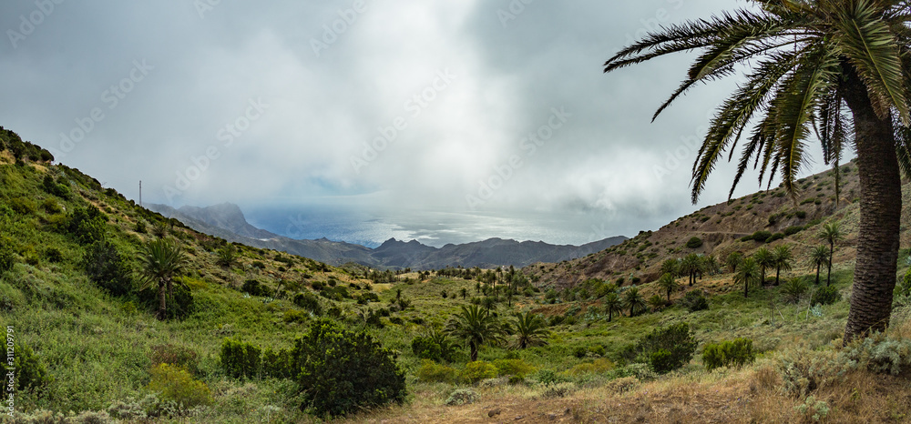 Rocky coastline with sharp cliffs in the ocean on the North of La Gomera island near Arguamul village where you can get along the narrow winding serpatine. Canary Islands, Spain Rocky coastline with sharp cliffs in the ocean on the North of La Gomera island near Arguamul village where you can get along the narrow winding serpatine. Canary Islands, Spain