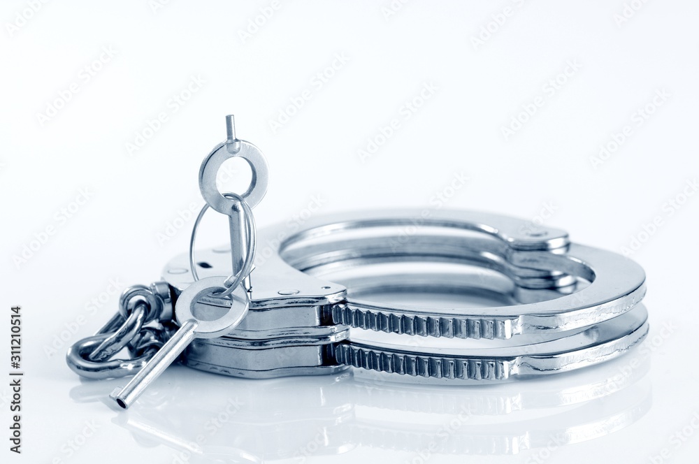 Close-up of metal handcuffs and key in keyhole Close-up of metal handcuffs and key in keyhole