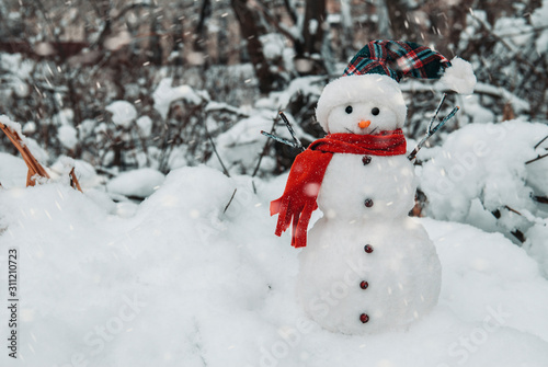 Snowman with cap and scarf in snowdrifts 