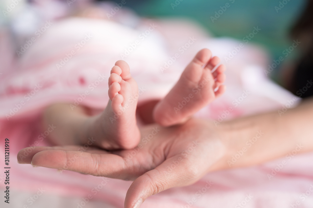 Baby foots on mother hand.Newborn baby feet and relax action with pink blanket.Happy time family concept. Baby foots on mother hand.Newborn baby feet and relax action with pink blanket.Happy time family concept.