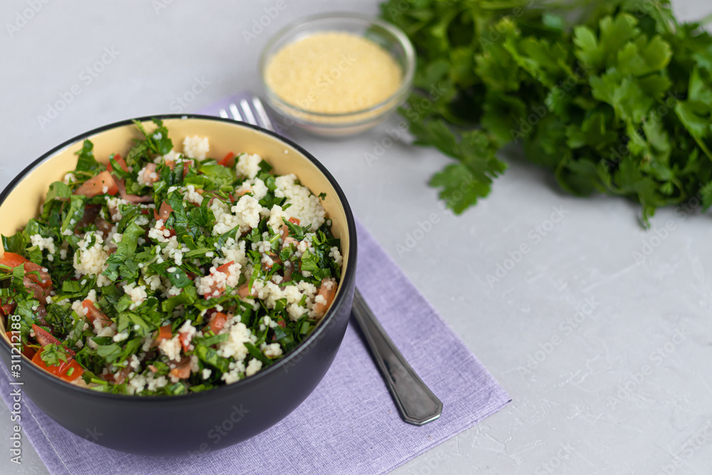 Tabule salad in a round plate on a light gray background under concrete. Tabule salad in a round plate on a light gray background under concrete.