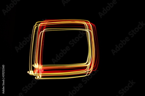 Long exposure photograph of a square outline box shape in neon colour in an abstract swirl, parallel lines pattern against a black background. Light painting photography.