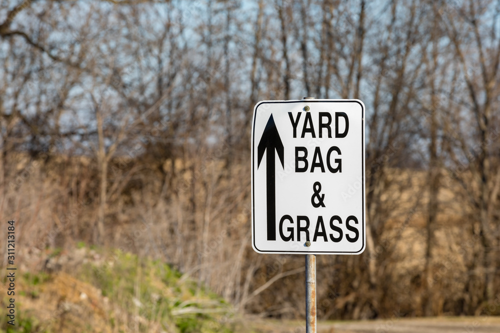 Leaf, yard bag, and grass clippings directional sign with arrow at city yard waste disposal, dump site