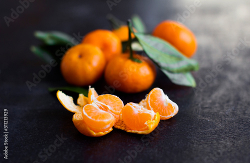  tangerines with leaves on a black background