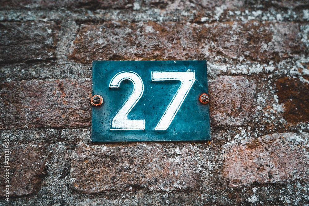 House number 27 on brick wall with numbers twenty seven on blue metal plate enameled House number 27 on brick wall with numbers twenty seven on blue metal plate enameled