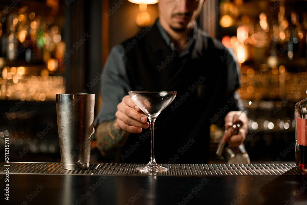 Bartender grabbing a cocktail glass for martini Bartender grabbing a cocktail glass for martini