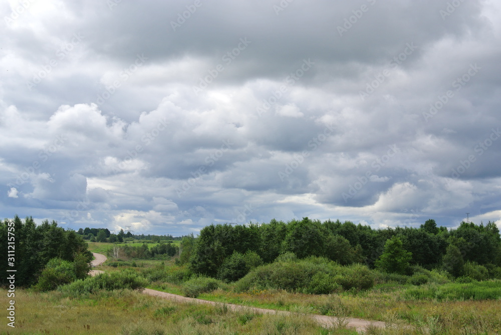 summer landscape with sandy road, fields on hills and Cumulus clouds