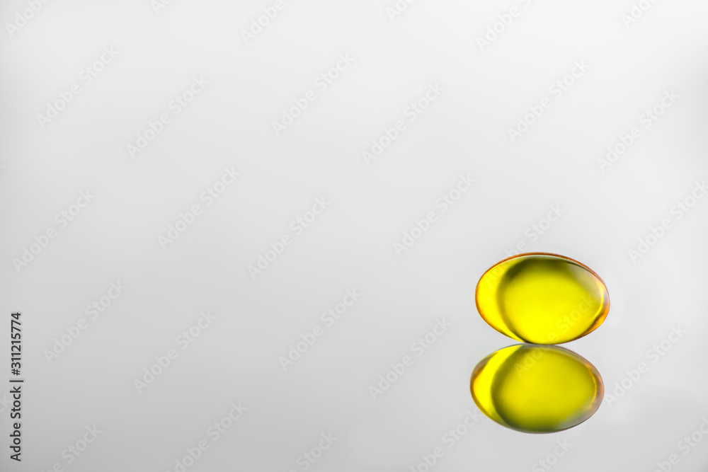 gelatinous yellow capsule on a gray background. vitamin gelatinous yellow capsule on a gray background. vitamin