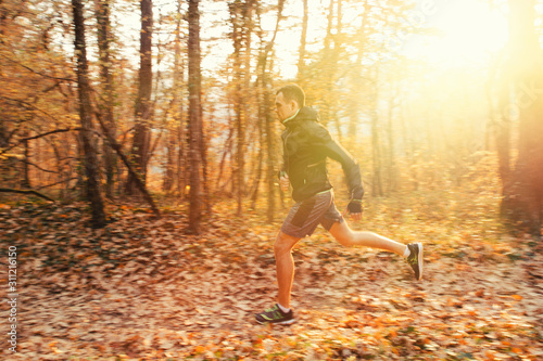 The concept of sports and cross-country running. A man in sports clothes is engaged in running in the autumn Park. Sunlight. Copy space