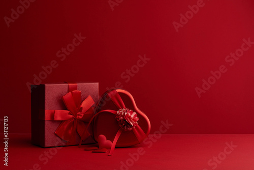 Red surprise gift boxes with ribbon in the shape of heart gifts with love for Valentine's Day or Christmas on scarlet background