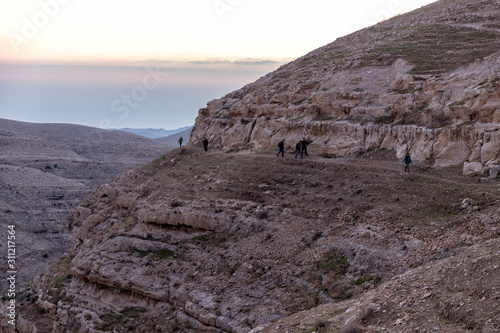 mountains in mar saba at sunrise with tourists hiking photo