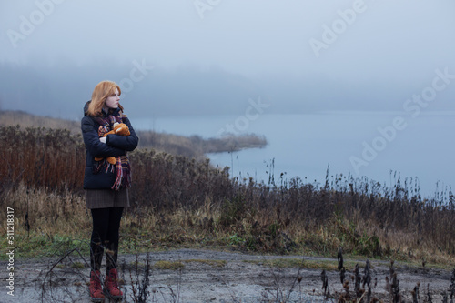 Sad blonde teenager  girl hugging  teddy bear by foggy  lake.  Concept of adolescence and adolescent problems. © Maya Kruchancova