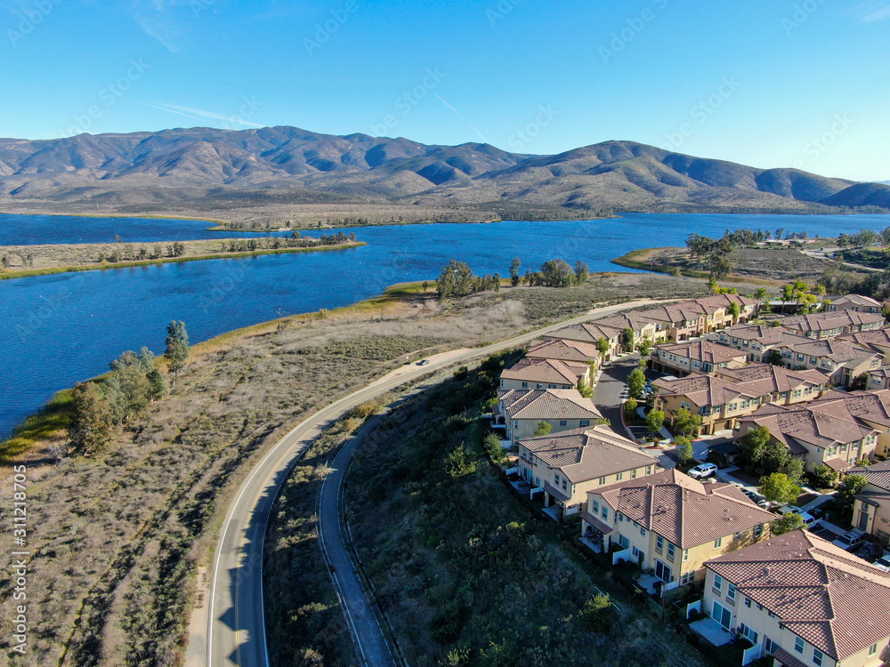 Aerial view of identical residential subdivision house with big lake and mountain on the background during sunny day in Chula Vista, California, USA.