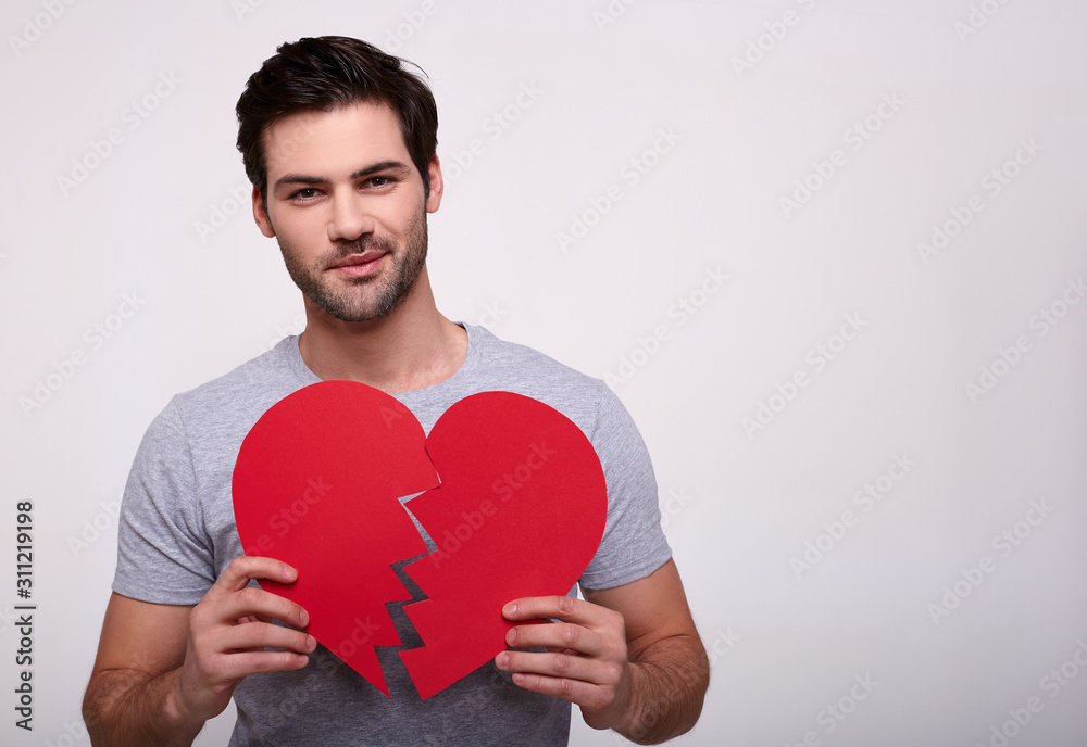 Portrait of a handsome young man with a broken heart in his hands. Portrait of a handsome young man with a broken heart in his hands.