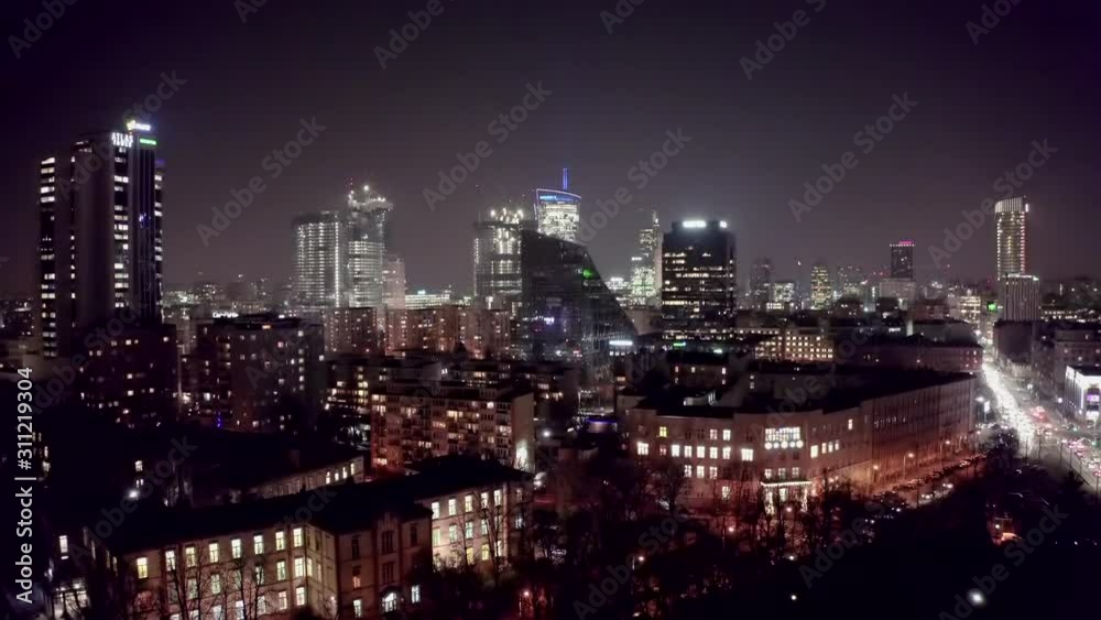 Drone shot at night cityscape with skyscrapers and buildings on a foggy night. Warsaw-Poland. 04. December. 2019. Aerial view of the night city with traffic and skyscrapers in the fog. Drone shot at night cityscape with skyscrapers and buildings on a foggy night. Warsaw-Poland. 04. December. 2019. Aerial view of the night city with traffic and skyscrapers in the fog.
