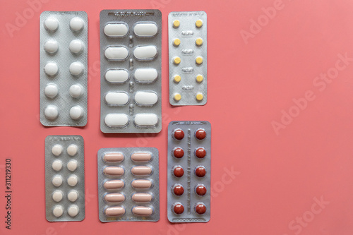 different blisters with tablets on pink background