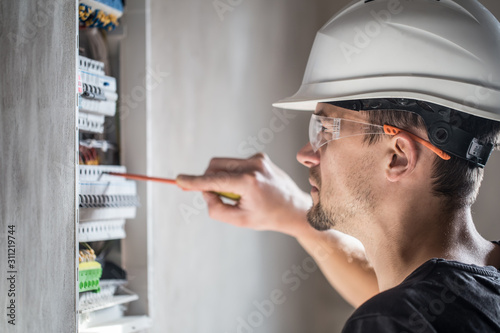 man, an electrical technician working in a switchboard with fuses. Installation and connection of electrical equipment. Close up.