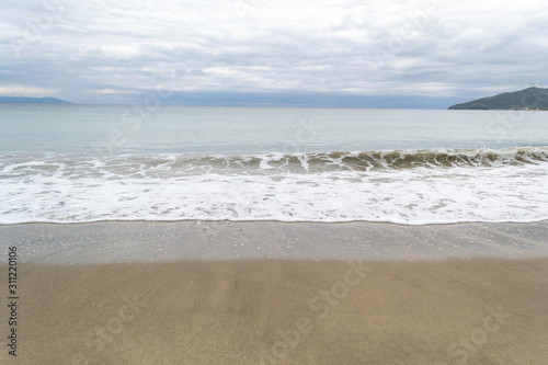 Long calm waves at sea shore over cloudy sky © Aleksandar