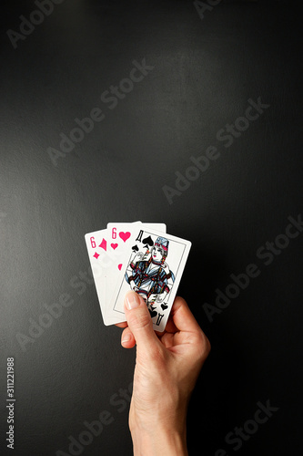 Cards in a hand on a black background. Three Card Poker. Rules and combinations of the game. Pair