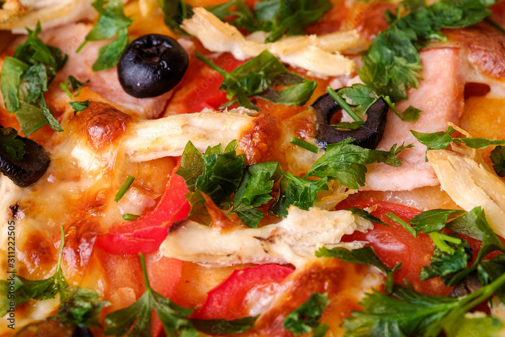 Fresh hot homemade pizza with chicken meat, ham, tomato, mozzarella cheese, black olives and parsley, macro view texture Fresh hot homemade pizza with chicken meat, ham, tomato, mozzarella cheese, black olives and parsley, macro view texture