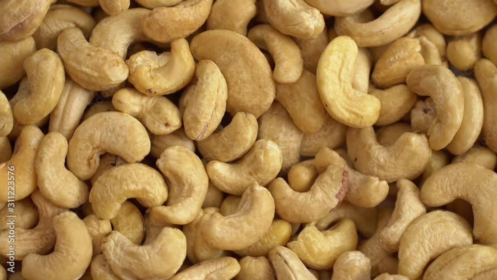 Cashew close up. product rich in minerals and vitamins. Cashew turns in a shot. Cashew kernels rotating. Cashew close up lies under beams of the sun. Macro 4K Cashew close up. product rich in minerals and vitamins. Cashew turns in a shot. Cashew kernels rotating. Cashew close up lies under beams of the sun. Macro 4K