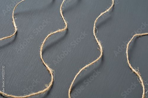 Old curly brown rope lies on dark concrete desk in workshop. Close-up