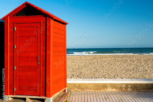 red beach hut cabin with see and beach on the background photo